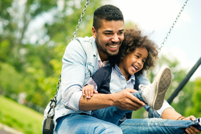 Father and daughter playing on the swing